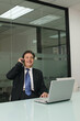 © ImageHit - Businessman talking on the phone while using laptop