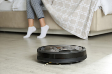 Sticker - Modern robotic vacuum cleaner and blurred woman on background