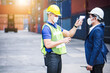 © totojang1977 - Scan checking virus Covid 19 by digital thermometer before enter work to protect voronavirus at container yard during Coronavirus crisis. Engineer industrial and factory concept.