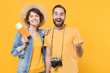 Wall Mural - Cheerful tourists couple friends guy girl in summer clothes hat photo camera isolated on yellow background. Passenger traveling abroad on weekends. Air flight journey concept. Hold passport tickets.