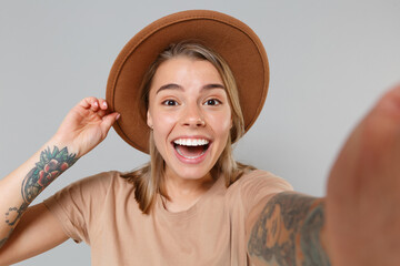 Wall Mural - Close up of excited young blonde woman girl in casual beige t-shirt hat posing isolated on gray wall background studio. People lifestyle concept. Mock up copy space. Doing selfie shot on mobile phone.