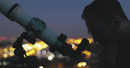 Wall Mural - astronomer with a telescope watching at the stars and moon with blurred city lights in the backgroun