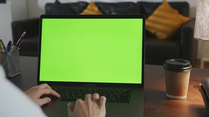 Woman working in office and using laptop with looking at green screen.