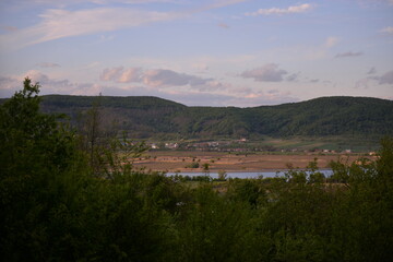 landscape with forest and lake. houses located near a field ready for cultivation