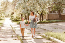 Young Smiling Mother With Daughter And Son Walk In The Park