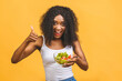 © denis_vermenko - Healthy food concept. Close-up Of Beautiful African American black Woman Eating Salad isolated over yellow background. Thumbs up.