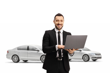 Poster - Man in a suit with a laptop computer smiling at the camera and posing in front of cars