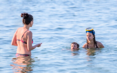 mother with children in sea. family swim on the waves in ocean. mom teaches son how to swim.