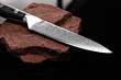 A large kitchen knife with a black handle on a dark background. Knife with a wide sharp blade. Scratched steel surface of the knife blade.