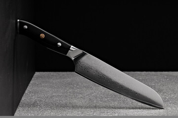 Wall Mural - A large kitchen knife with a black handle on a dark background. Knife with a wide sharp blade. Scratched steel surface of the knife blade. 