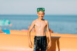 © Shopping King Louie - Small smiling child boy in swimming glasses, on the sea sand of the beach. Summer holiday
