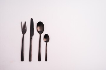 Wall Mural - Closeup shot of a knife, fork, and two spoons isolated on a light-colored background