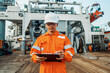 © Igor Kardasov - Filipino deck Officer on deck of offshore vessel or ship , wearing PPE personal protective equipment. He fills checklist. Paperwork at sea