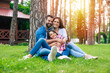 © My Ocean studio - Beautiful happy family while sitting together on the grass and hugging each other, relaxing outdoors on suburban house background.