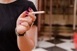 © A - Woman with pink nails and silver ring smoking a cigarette and dark background