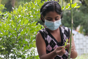 masked girl playing outdoor while keeping social distance during the global pandemic.