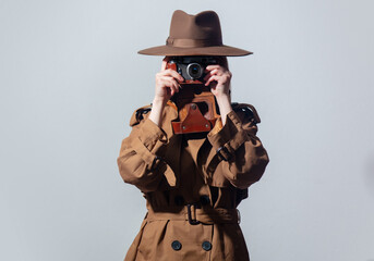 Poster - Woman in hat and cloak as a spy with camera on gray background.