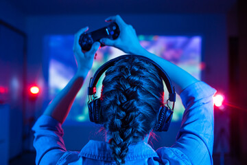 Wall Mural - Gemer player plays a game on a large screen with the help of a joystick, creative light, streamer, streaming games and a blogger