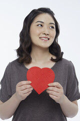 Cheerful woman holding up a red heart shape