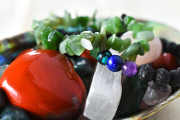 Wall Mural - A close up image of a jade bracelet and a chakra bracelet in a bowl filled with healing crystals. 