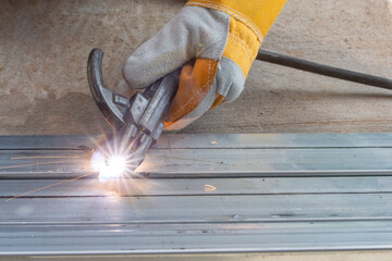 Wall Mural - The welder is welding the various parts of the house construction.