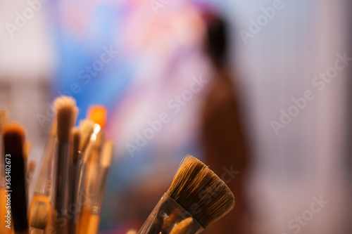 Fotografía Close up of paint brushes and artist in the background
