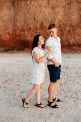 Wall Mural - Loving couple in white clothes during a honeymoon at sea walk on the sand at a photoshoot Love Story, ocean coast, beach