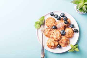 Wall Mural - Dutch mini pancakes called poffertjes with blueberries, sprinkled with powdered sugar. Healthy food concept with copy space. Top view.