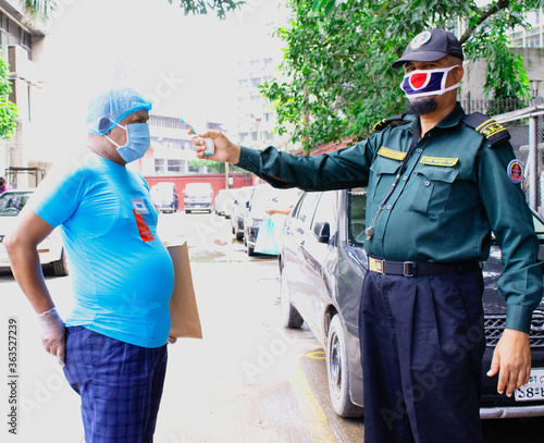 Coronavirus epidemic. Dhaka, Bangladesh - July 07 2020: Security personnel checking temperature before entering the Safety Area. Security procedures.
