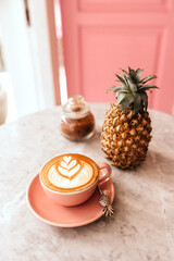 Wall Mural - Pink cup of cappuccino on marble table background. Love latte art on the top of it.