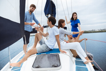 Group of happy friends drinking vodka cocktails at boat party outdoor, cheerful and happy. Young people having fun in sea tour, youth and summer vacation concept. Alcohol, vacation, resting.