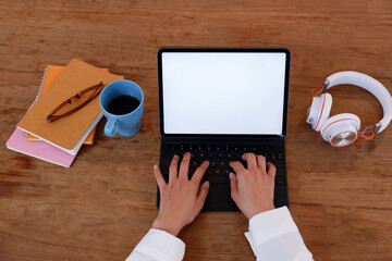 Poster - Close-up shots at the hands of female businesswomen are typing documents using a notebook computer on a wooden table with a coffee cup placed on the side in the office in the morning.