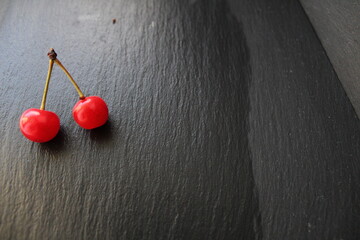 two cherries cherries are lying on a gray stone black background background for food