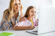 © LIGHTFIELD STUDIOS - Selective focus of smiling woman embracing cheerful daughter during electronic learning