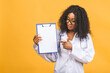 © denis_vermenko - Medicine, profession and healthcare concept - smiling african american female doctor in white coat with clipboard and stethoscope isolated over yellow background.