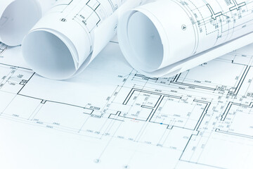 set of construction plans and blueprint rolls with technical project drawings on architect workplace desk