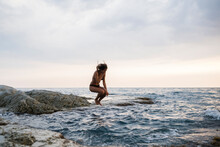 Woman Jumping Into The Sea At Sunset