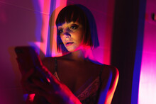 Beautiful Girl Using Her Smartphone On The Neon Light.