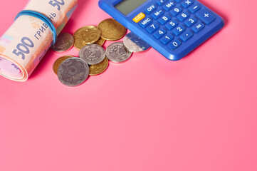 Ukrainian banknotes and metal coins near calculator on pink background