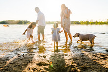 Family Playing On The Shore Of A Lake In Summer