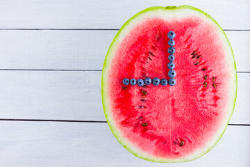 Wall Mural - Watermelon and blueberries on white background. Half of watermelon on wooden boards. Berries for vegan. Clock hands of berries. Watch from food