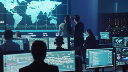 Project Manager and Computer Science Engineer Talking while Using Big Screen Display Showing Global Map and Data. Telecommunications Company System Control and Monitoring Room.
