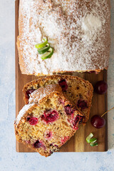 Poster - Slices of homemade pound cake with cherries and nuts on wooden cutting board. Light blue stone background. Top view.