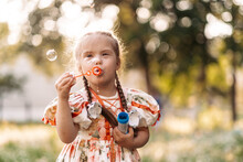 A Girl With Down Syndrome Blows Bubbles. The Daily Life Of A Child With Disabilities. Chromosomal Genetic Disorder In A Child.
