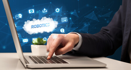 businessman working on laptop with robotics inscription, modern technology concept