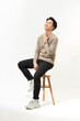 © makistock - Full body Asian man sitting on high chair over white background