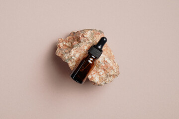 Wall Mural - Amber glass dropper bottle with essential oil for hair care on stone on beige background. Flat lay, top view. Cosmetic packaging mockup. Flat lay, top view, overhead.