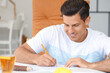 © Pixel-Shot - Young man coloring pictures at home