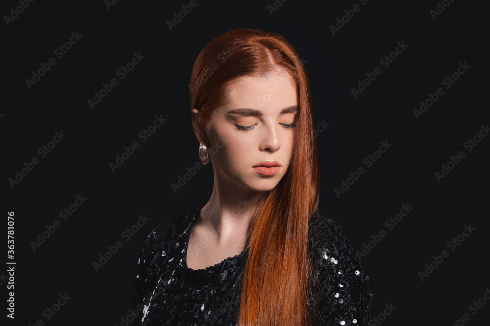Beautiful young redhead woman on dark background