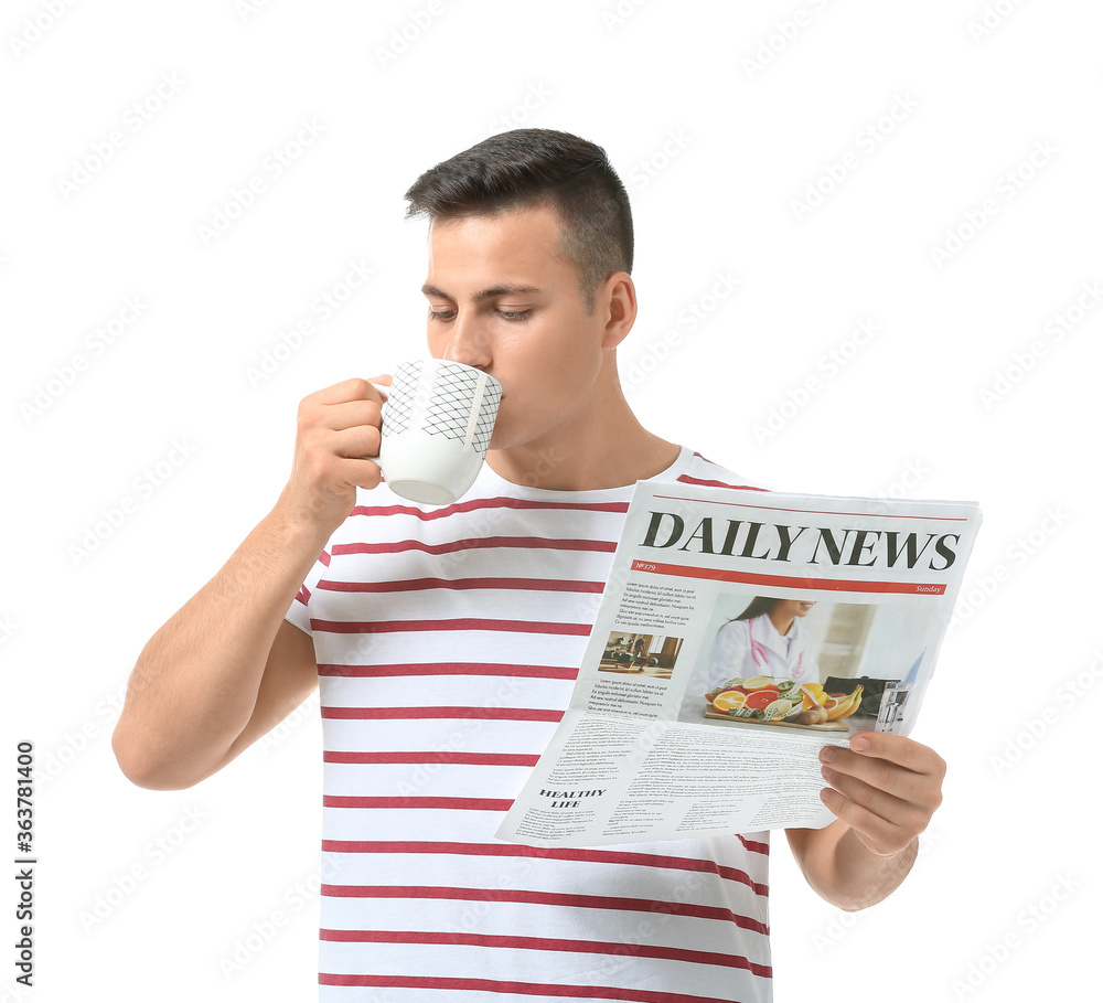 Handsome young man with cup of tea and newspaper on white background